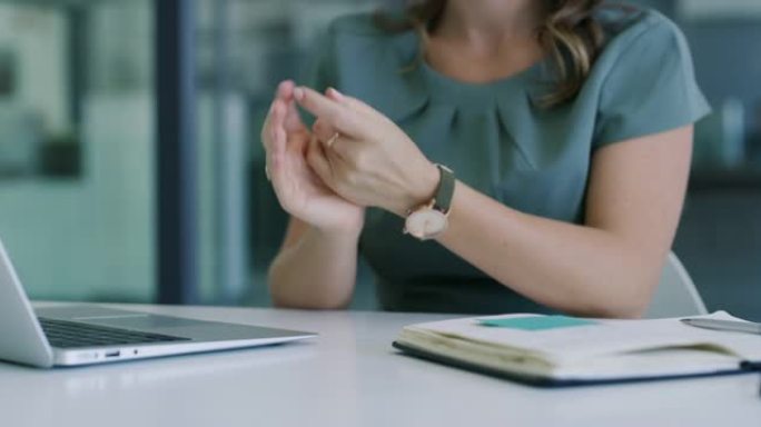 4k视频片段，一位无法识别的女商人在现代办公室的办公桌前对双手进行消毒