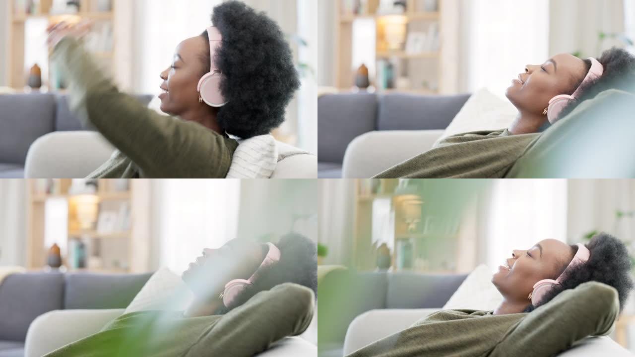 年轻女子在家里的沙发上放松时听音乐。无忧无虑，开朗快乐的女性戴着耳机，一边欣赏播客和喜欢的歌曲。休息