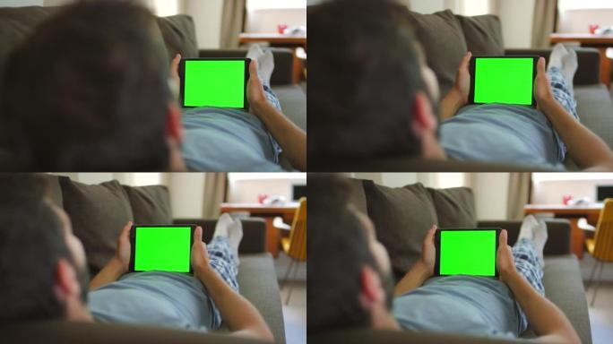 4k视频片段，一名男子使用数字平板电脑躺在沙发上