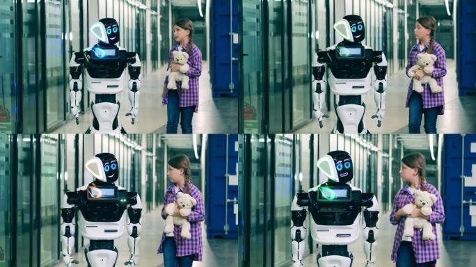 十几岁的女孩正在和一个机器人说话，并向它展示她的泰迪熊