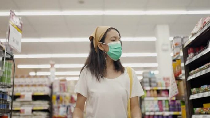 戴着防护医用口罩的年轻女子正在选择在超市购买商品。