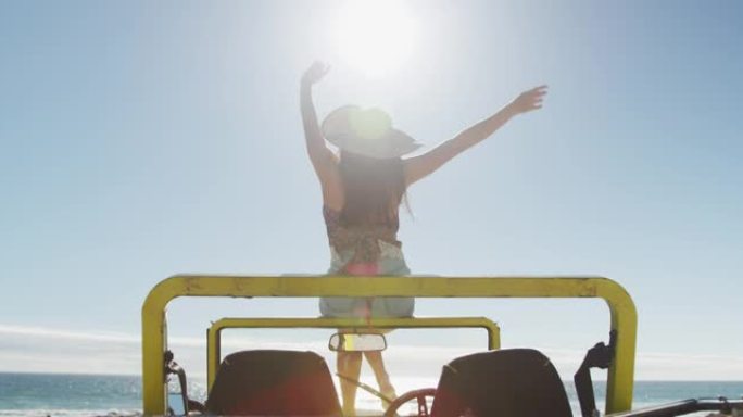 快乐的白人妇女坐在海边的沙滩车上挥舞着双手