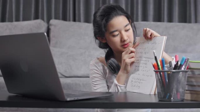 特写迷人的亚洲少女通过笔记本电脑向朋友解释数学作业。她在冠状病毒锁定的同时在家使用在线视频通话教学数