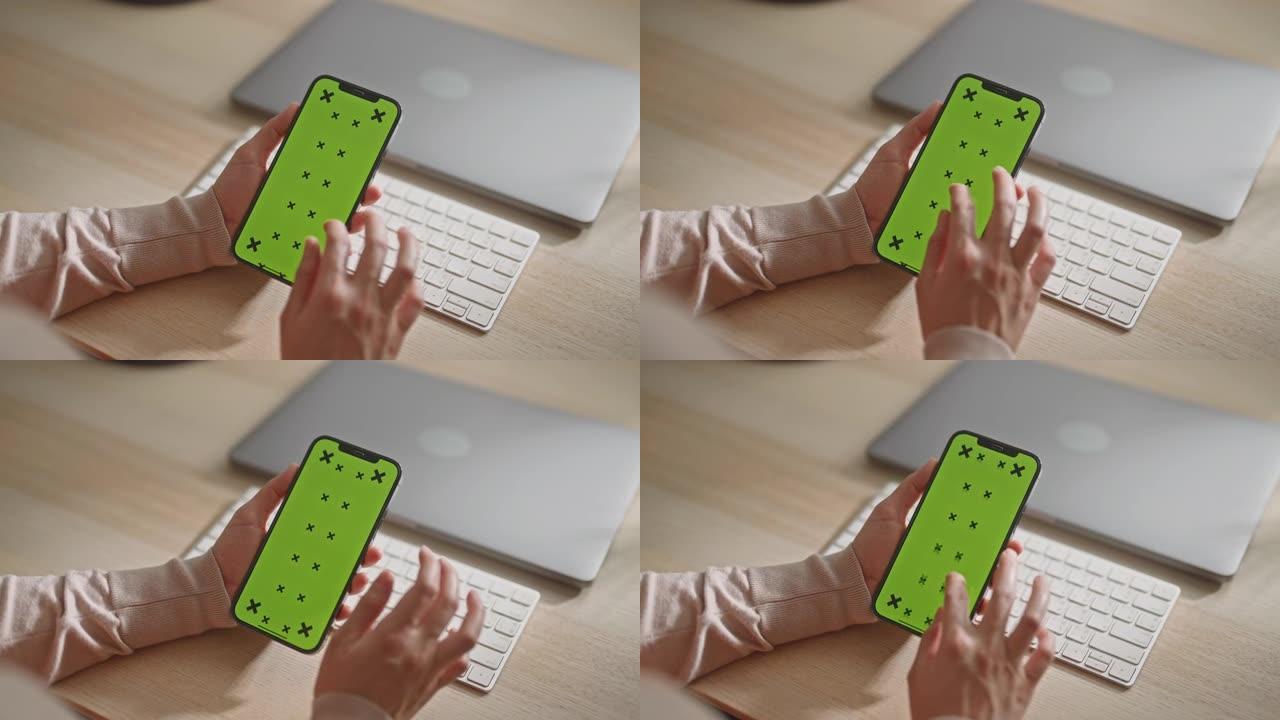 女人手持绿色触摸屏的智能手机