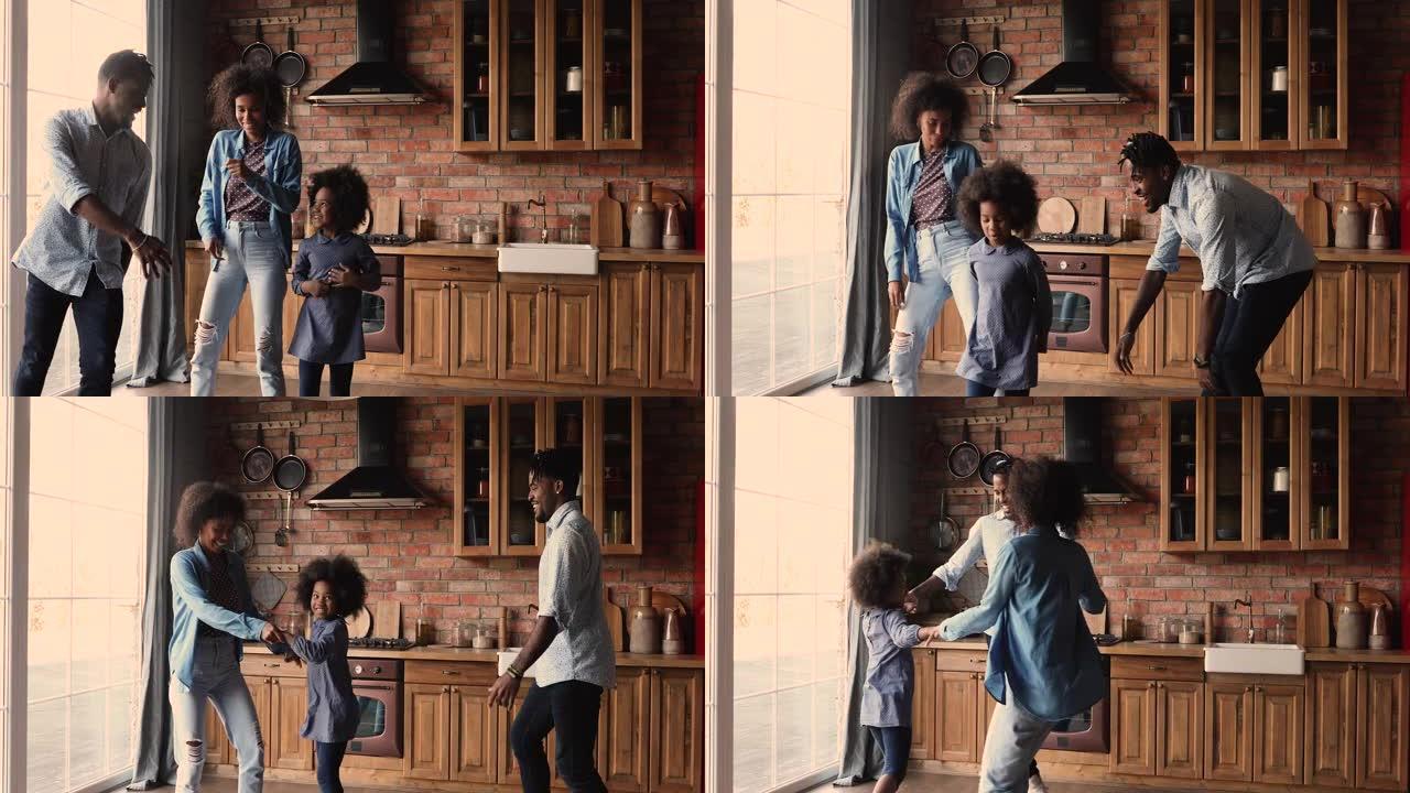 非洲夫妇和小女儿在现代舒适的厨房里跳舞
