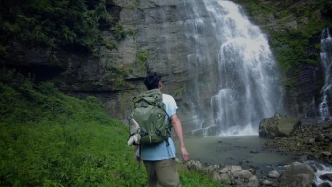 山间瀑布前的游客背包客旅游视频素材高山流