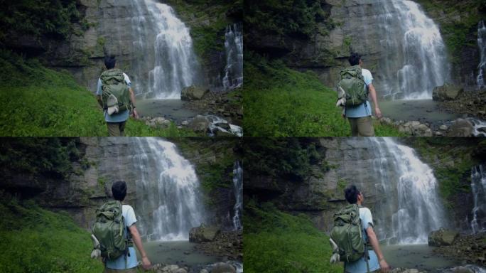 山间瀑布前的游客背包客旅游视频素材高山流