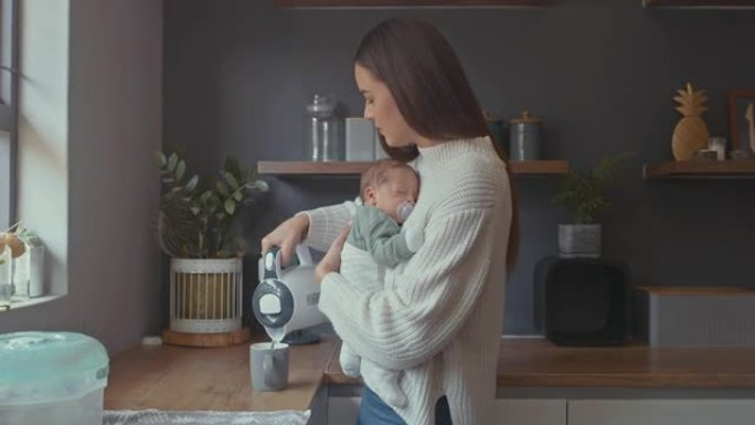 4k视频片段，一名妇女在制作热饮料时抱着婴儿