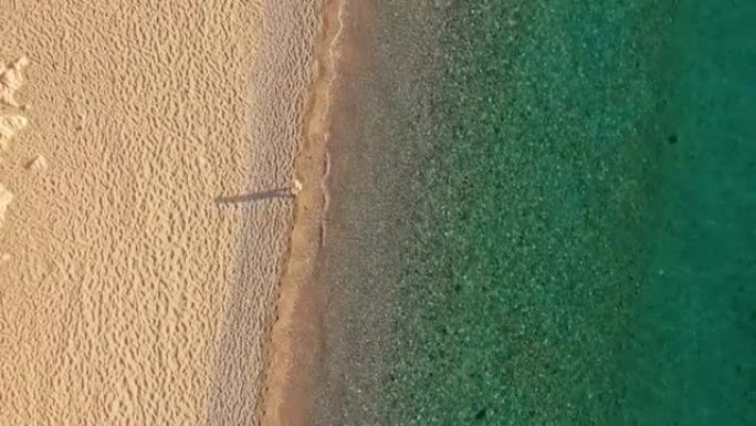 一个沿着海滩散步的人的鸟瞰图，意大利撒丁岛。卡拉卢娜洞穴。