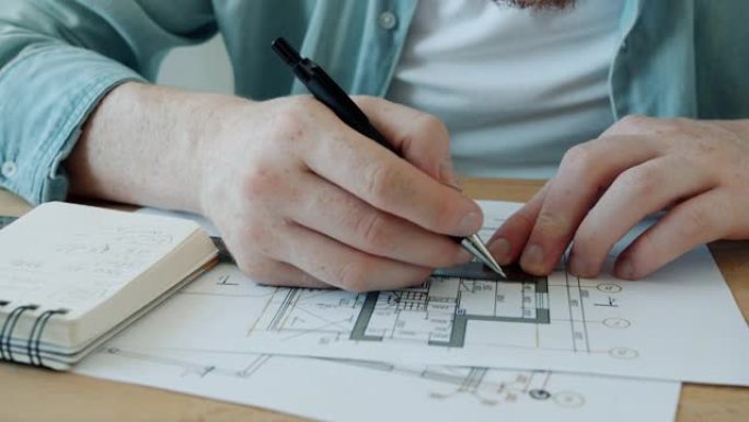 建筑师使用蓝图时，用标尺测量建筑平面图的男性手的特写