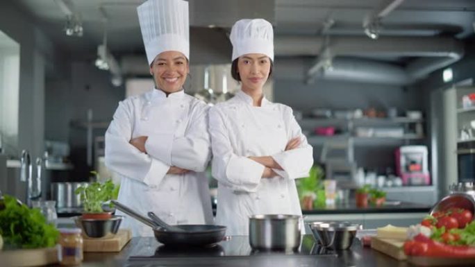 世界著名餐厅: 亚洲和黑人女厨师摆姿势的肖像，看着相机。两位专业人士烹饪美味而正宗的食物，在现代厨房
