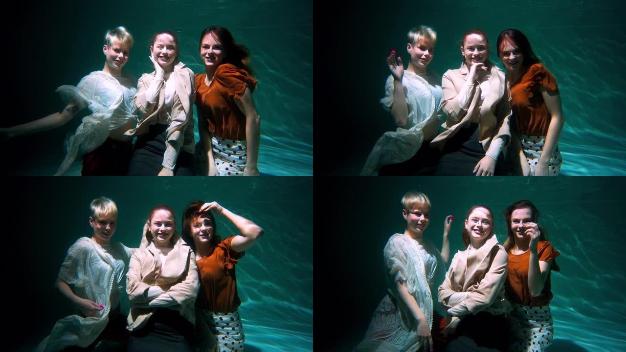 三个年轻美丽快乐的女人在波西米亚风衣服水下慢动作的镜头前微笑