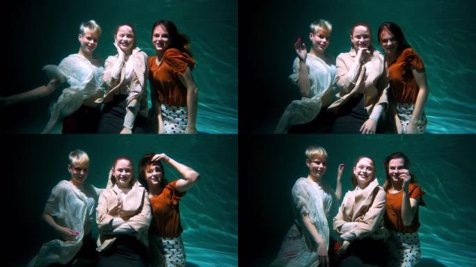 三个年轻美丽快乐的女人在波西米亚风衣服水下慢动作的镜头前微笑
