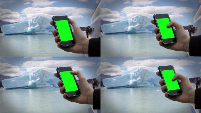男性的手在冰山附近使用旧的智能手机绿屏。