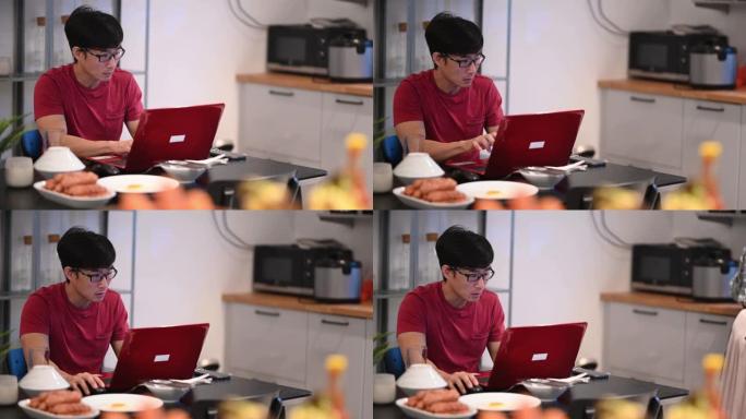 一名亚洲中国中年成年人在餐厅吃早餐，同时使用笔记本电脑回复电子邮件