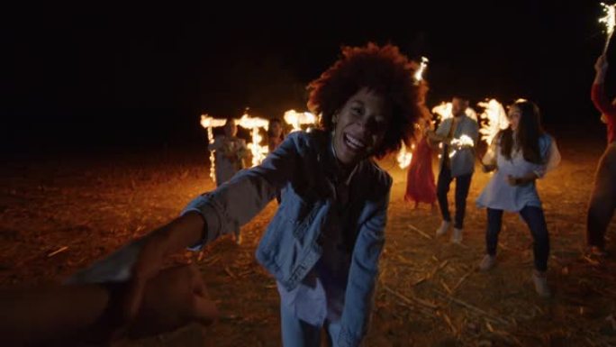 POV: 非裔美国女孩在户外派对上拉着她的朋友与一群年轻人跳舞的肖像。无忧无虑，欢迎快乐的多民族朋友