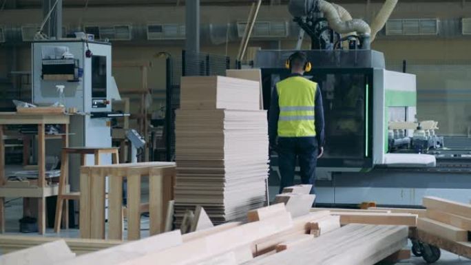 男人在工厂看用木材工作的工业机器。