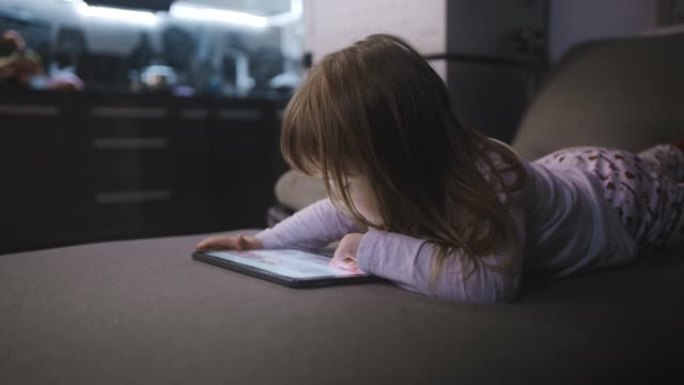 小女孩在家里沙发上使用数字平板电脑