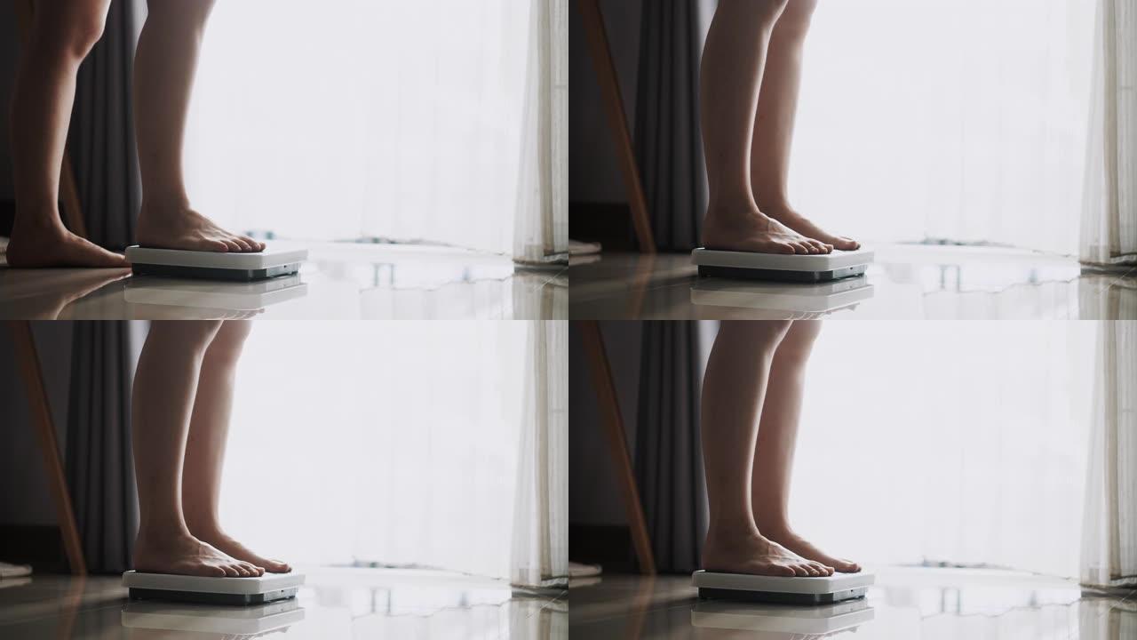 亚洲女性脚踩在数字体重秤上检查她的体重，体重秤