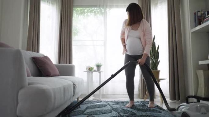 孕妇使用真空吸尘器清洁客厅