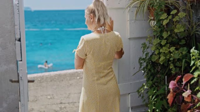 SLO MO女人站在海边公寓的入口门口时向某人挥手