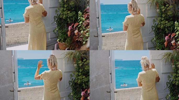 SLO MO女人站在海边公寓的入口门口时向某人挥手