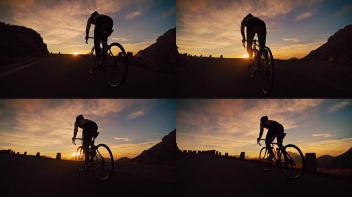 剪影骑车人在日出时在山路上坡骑自行车