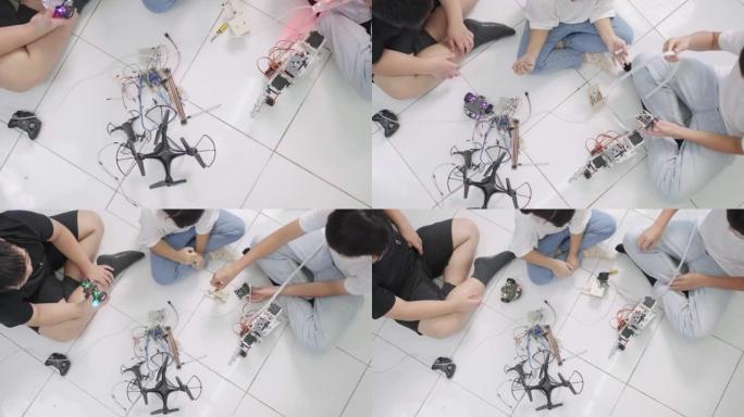 三个孩子在学校的机器人课上学习和玩他们的DIY机器人汽车和其他东西的俯视图。