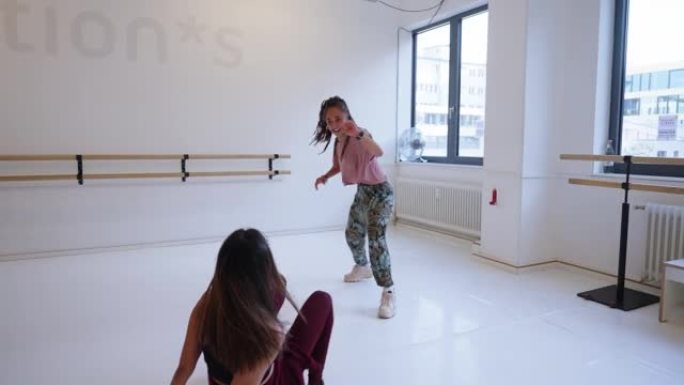 年轻女子在健身工作室向她的朋友展示舞蹈动作