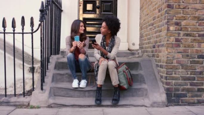 两个朋友坐在外面时使用手机的4k视频片段