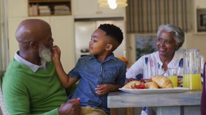 非裔美国男孩坐在家里的膝盖上给祖父喂草莓