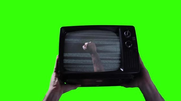 男性双手握着复古电视，在绿色屏幕上举起拳头。