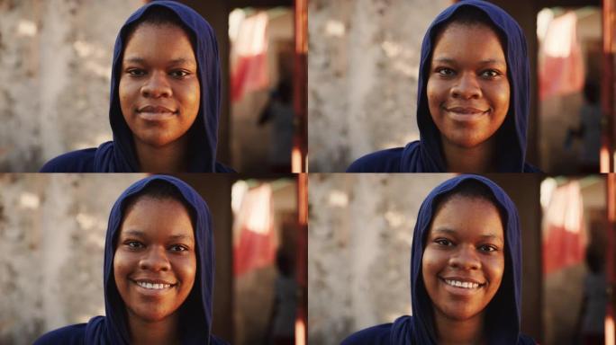 一位穿着传统服装的美丽非洲年轻女子的肖像认真地看着相机，然后微笑着。年轻害羞的女村民代表她的文化
