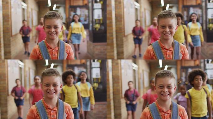 快乐的高加索小学生站在走廊上看着相机的肖像