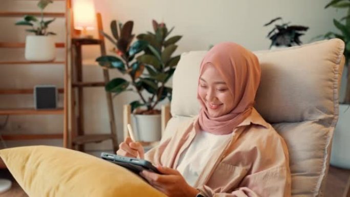 在家里工作的亚洲穆斯林女商人享受快乐。