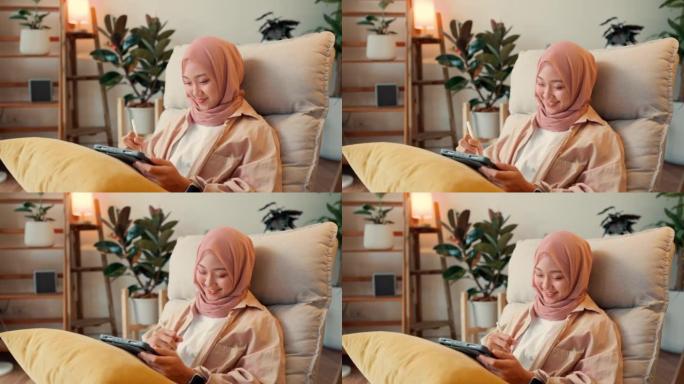 在家里工作的亚洲穆斯林女商人享受快乐。