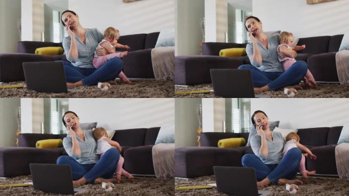白人母亲在家工作时抱着婴儿在智能手机上聊天