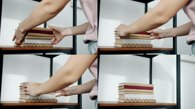 女性双手的特写镜头将一堆书放在木架子上