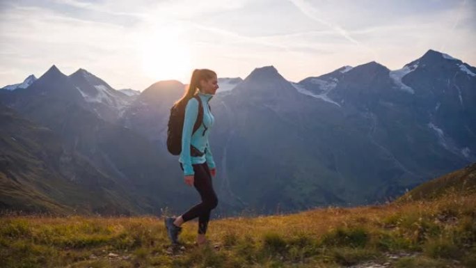 适合年轻女子徒步登山小径，日落时背景为雄伟的山峰