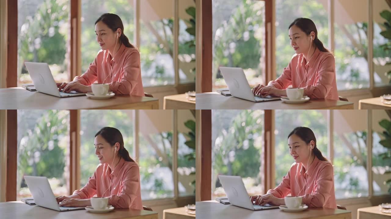 穿着休闲服装的亚洲女性在咖啡店工作时使用笔记本电脑