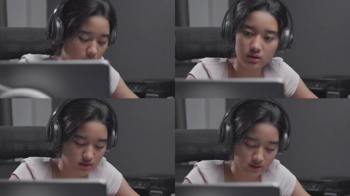 4k分辨率迷人的亚洲少女戴着耳机，在冠状病毒或covid 19锁定时，与老师一起在笔记本电脑上进行在