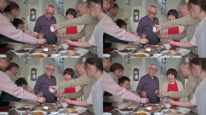 亚洲华人mutli世代家庭在团圆饭中与传统美食Lou sang (生鱼菜) 庆祝除夕
