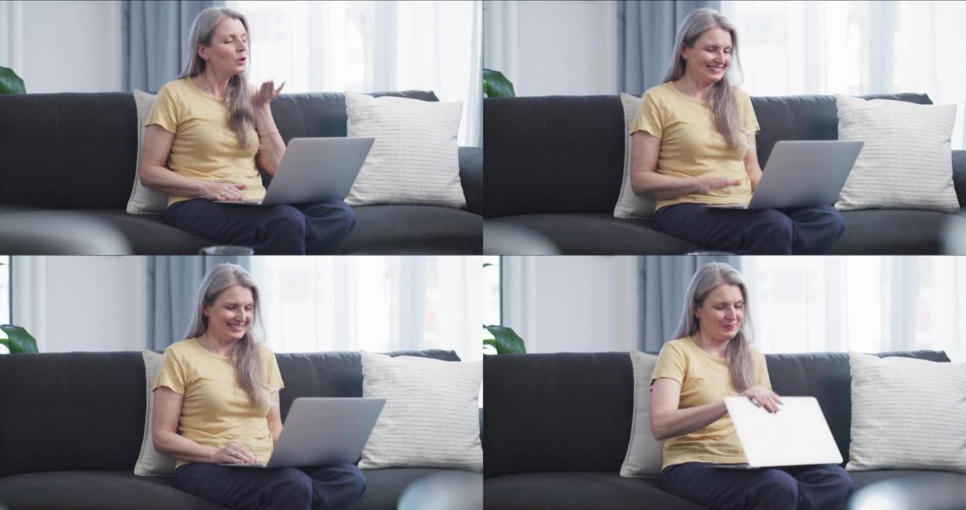 4k视频片段，一个迷人的成熟女人坐在休息室里用笔记本电脑进行视频聊天