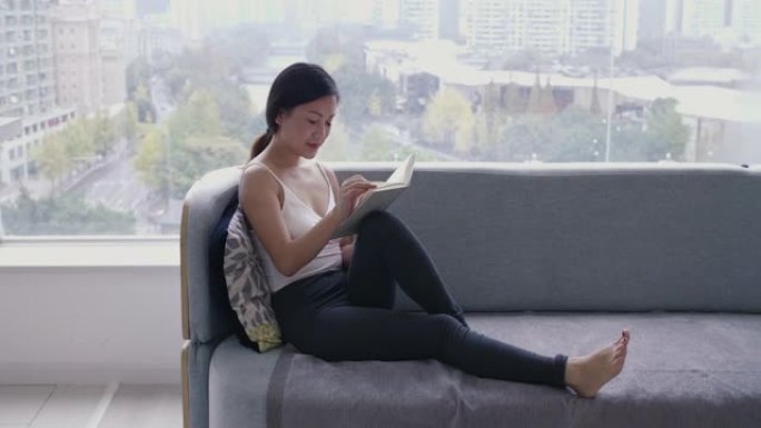 年轻的亚洲妇女在家中的教练读书