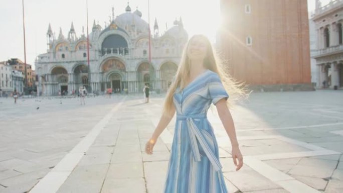 美丽的镜头耀斑肖像快乐微笑的年轻白人妇女在威尼斯空旷的日出圣马可广场摆姿势。