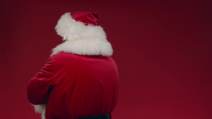 一个阴郁的圣诞老人，双臂交叉在红色背景上转过身，最后微笑