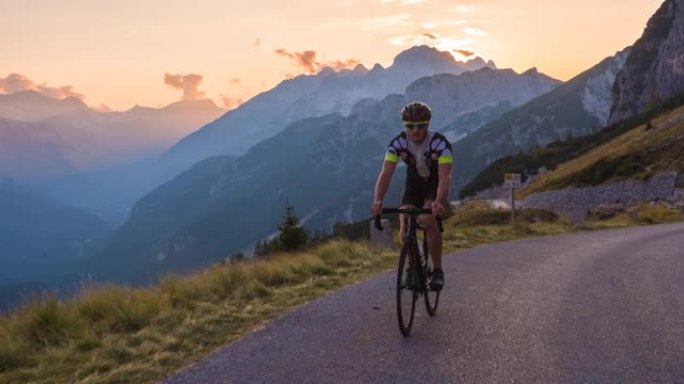 健康的男性公路自行车手骑自行车在黄昏的美好一天上坡风景秀丽的山路
