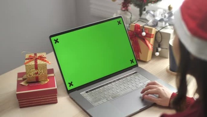 戴圣诞老人帽子的女人使用笔记本电脑绿屏