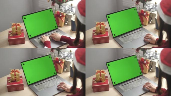 戴圣诞老人帽子的女人使用笔记本电脑绿屏