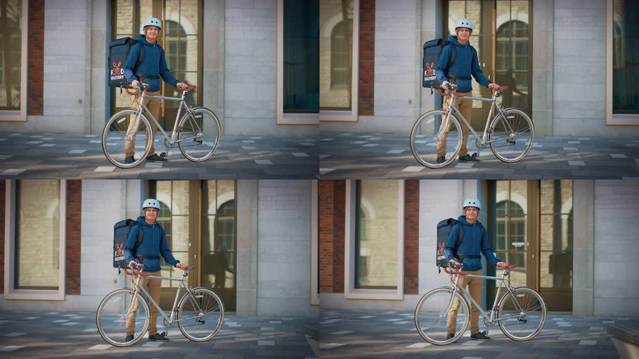 穿着保暖背包和安全帽的英俊送餐男子站在时尚的现代市区的自行车旁边。微笑快递员安全送达餐厅订单的肖像